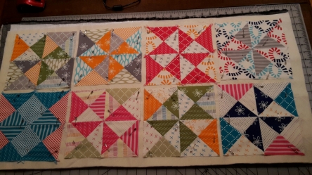 The charm pack made eight potholders.  Onto a large piece of backing, I placed one layer of Insul-bright and one layer of 100% cotton batting.  Pinned all of the potholders down and then straight-line quilted with a walking foot.